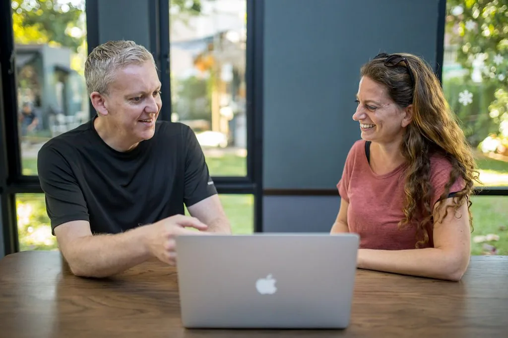 Stu Jordan at a laptop, explaining something to a smiling business owner